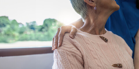 Caregiver or nurse put hands around shoulder of elderly patient for support
