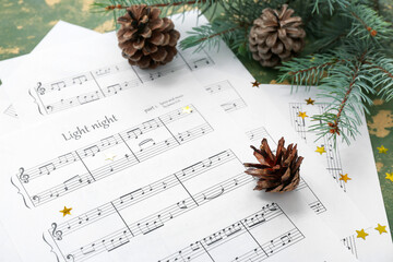 Composition with music sheets, cones and fir branches on color background, closeup