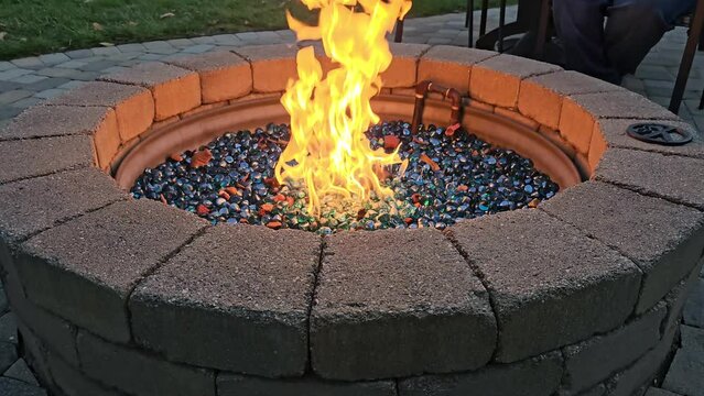 Stone fire pit with flames in glass rocks fueled by propane gas