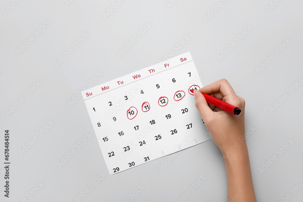 Wall mural Woman marking her period in menstrual calendar on grey background