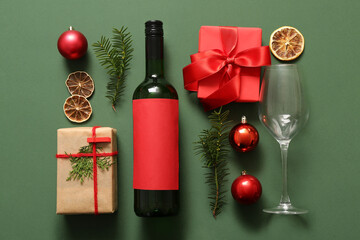 Bottle of wine with glass and Christmas gift boxes on green background