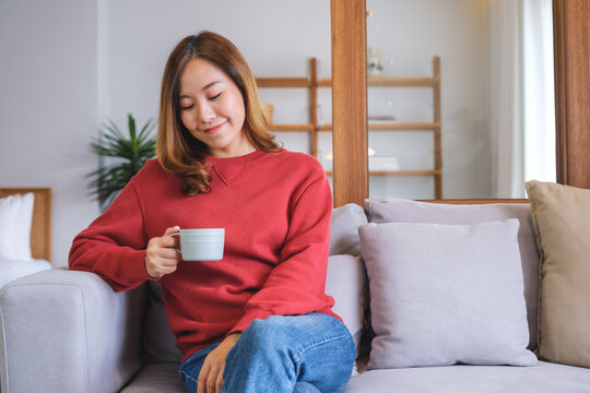 Portrait image of a beautiful woman holding and serving a cup of hot coffee at home