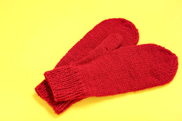 Stylish warm mittens on yellow background