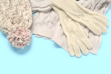 Warm gloves, scarf and hat on color background