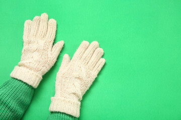 Female hands in warm gloves on green background, closeup