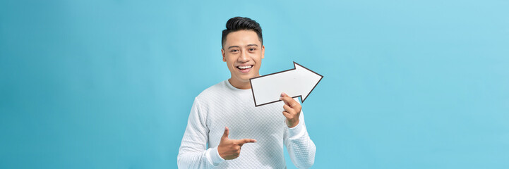 Young man holding an arrow isolated on blue background