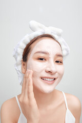 Banner of confident lady in towel on head, touching her face with clay mask