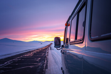 A van for traveling in the winter when the roads are covered with snow at dusk.