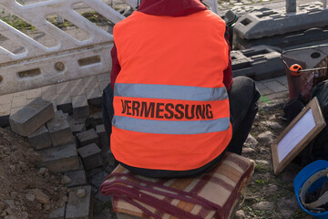 Auf einer Baustelle  ist ein Arbeiter von der Vermessung mit einer Weste
