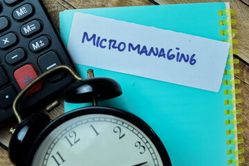 Concept of Micromanaging write on sticky notes isolated on Wooden Table.