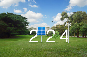 2024 white text with solar cell, wind turbine and growing tree on green grass field in public park, Happy new year 2024 ecological cover concept
