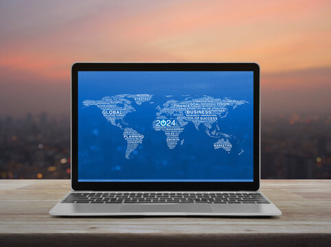 Start up 2024 business icon with words world map on laptop computer screen on table over cityscape on warm light sundown, Happy new year 2024 start up online, Elements of this image furnished by NASA