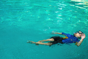 Active little girl floating and swimming in the pool. Copyspace.