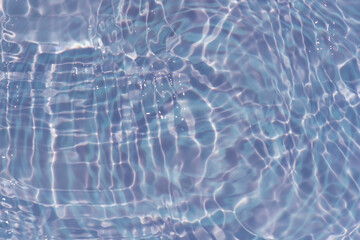 Defocus blurred transparent blue water drops on surface texture with splashes reflection. Trendy abstract nature background. Water waves in sunlight with copy space. Blue watercolor shine.