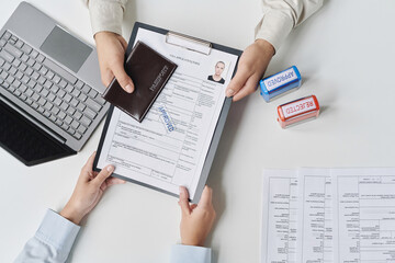 Top view of tourist getting approved visa from specialist in office