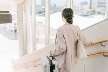 階段で重い荷物を持つ女性（駅・空港）

