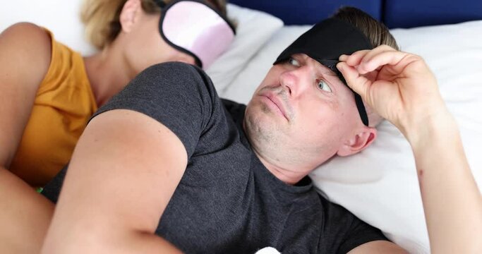 Waking up young man in sleep mask looking surprised at woman 4k movie. Promiscuous sex concept