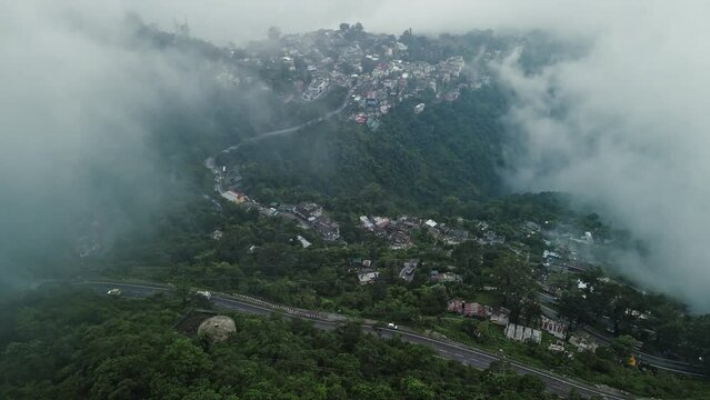 Aerial view of the town in the mountain, Narendra nagar, Tehri Garhwal, Uttarakhand, India. Hilly road in India during a foggy day. Transportation on a hilly Indian road during monsoon. 