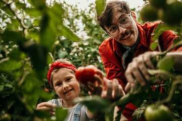 Portrait of a happy father and daughter taking care of their veggie garden together