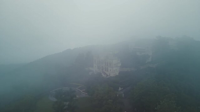 Aerial view of Narendra nagar Fort surrounded by green mountains during monsoon.Drone flying above the fort through green forest.