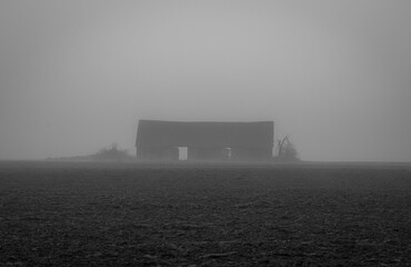 Old wooden warehouse in the mist in the middle on the field