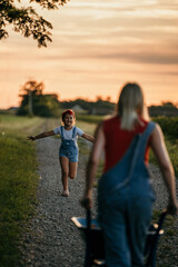 The excited daughter runs towards her mother in the countryside