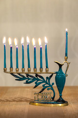 Menorah (Chanukkiah) with 8 lit burning candles for Jewish Hanukkah holiday on table at home. Celebrating Chanukah festival of lights.