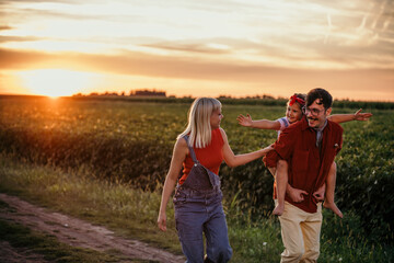 Happy family in the field at sunset in the summer or autumn