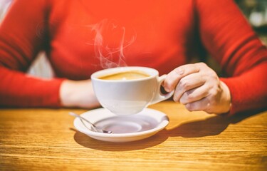 A girl drinks coffee at a table in a cafe

