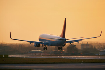 Airplane approaching for landing on airport runway. Passenger plane at golden light of sunset....