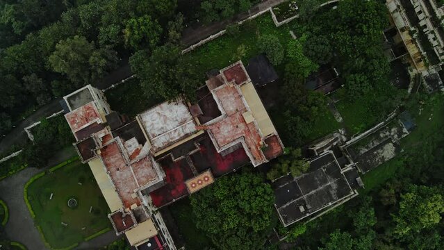 Aerial view of Narendra nagar Fort surrounded by green mountains during monsoon.Drone flying above the fort through green forest.