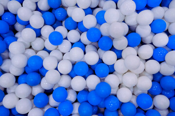 Blue and white plastic balls in ball pool at kids playground. Colorful plastic ball texture background. Many small colorful hollow plastic soft kids balls are in a ball pit.