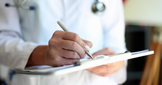 Female doctor nurse practitioner writing patient information. Cardiologist writing prescription in paper notepad and working with medical documents in clinic