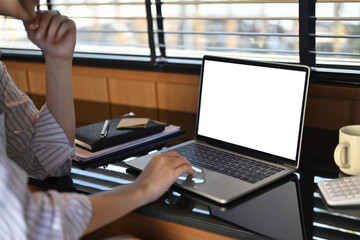 Fototapeta premium Side view of focused businesswoman working with laptop on desk in modern office
