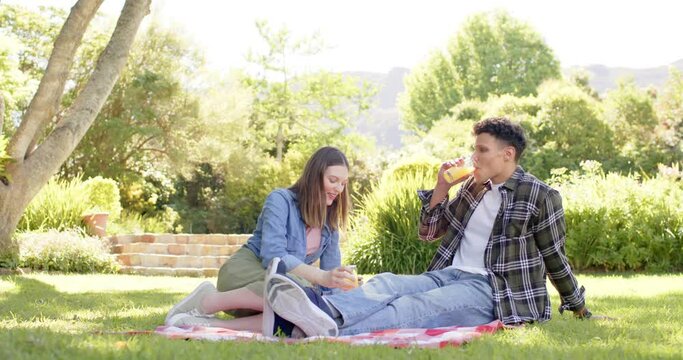 Happy diverse couple having picnic in sunny garden, in slow motion