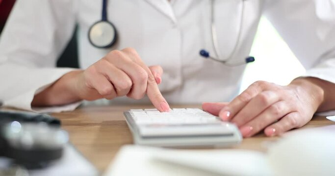 Doctor with calculator calculating costs and income in medical practice and hospital. Cost of health insurance