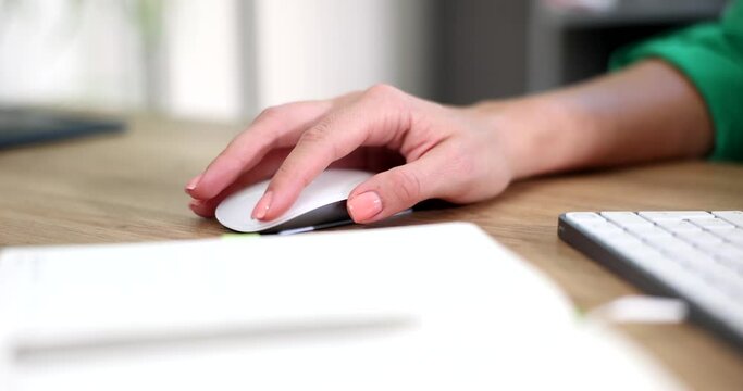 Closeup of female hand using white wireless mouse. Woman hand is using light wireless mouse and working remotely by freelancer from home