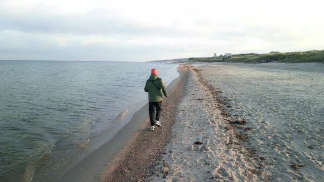 Ein junger Mann rennt an einem bewölkten Tag am Strand entlang. Ein Mann läuft am Sand entlang.