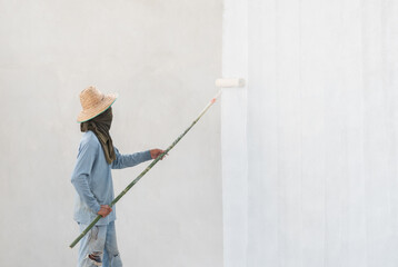 Worker painting wall with paint roller.