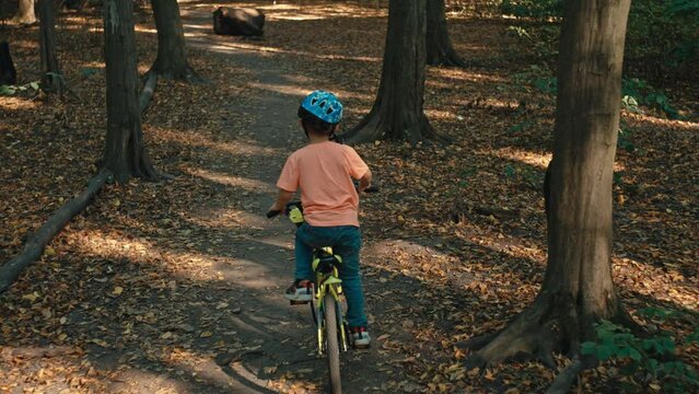 A boy child falls from a bicycle while riding in the park. The danger of active recreation is a child in a protective helmet. High quality 4k footage