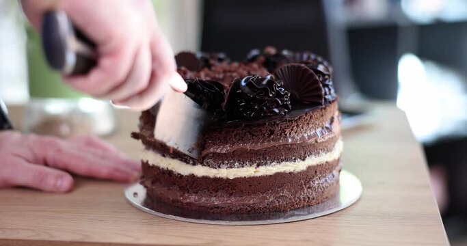 Cutting slice of birthday cake and closeup of knife cutting chocolate cake. Delicious fresh homemade cake