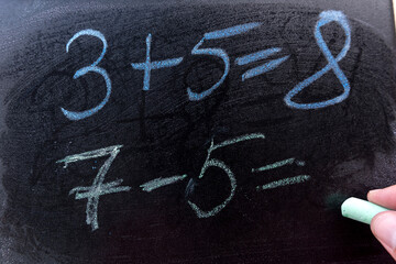 close up hand write primary simple mathematical equation. Math chalkboard