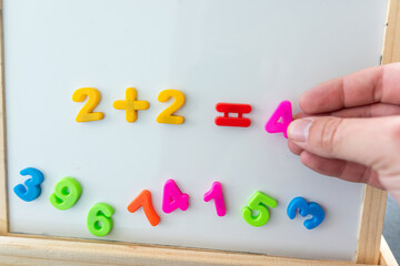 White board with magnetic numbers, primary school math. Solving examples