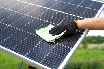 Male hand with cloth cleaning solar panel, concept of photovoltaic module maintenance