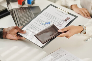 Close-up of man getting his approved documents for visa in visa agency