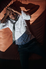 Top view of African American man having a headache he lyin gon sofa and holding his head