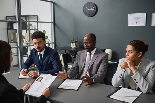 Group of specialists asking questions to applicant during interview for getting visa in office