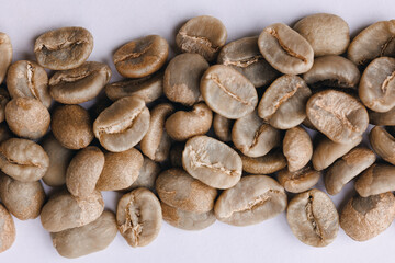 Macro fresh green raw roasting coffee beans, white isolated background