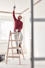 Handyman electrician with ladders working in a new home interior.