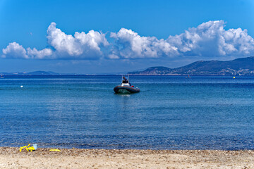 Scenic landscape with Mediterranean Sea and sandy beach and motorboat approaching of peninsula of Giens on a sunny spring day. Photo taken June 10th, 2023, Giens, France.